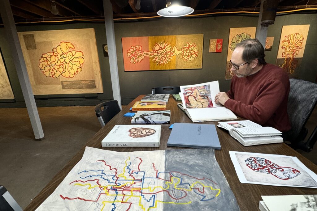 Man looking at books with drawings around him